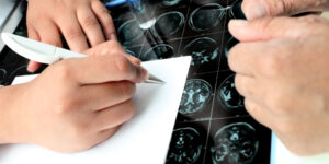 hands taking notes with brain scan images in the background